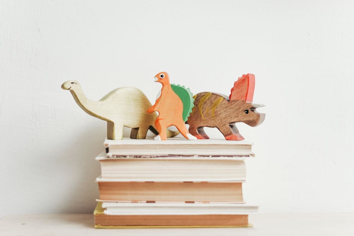 Wooden dinosaur toys lined up on a shelf